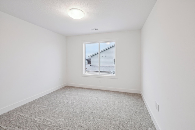 carpeted empty room featuring a textured ceiling