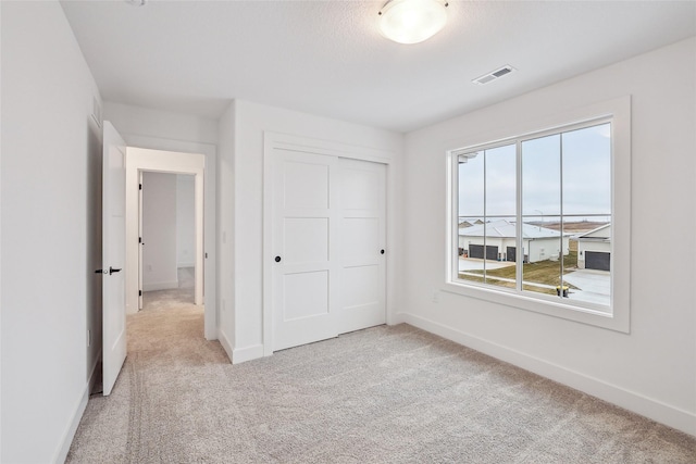 unfurnished bedroom featuring light colored carpet and a closet