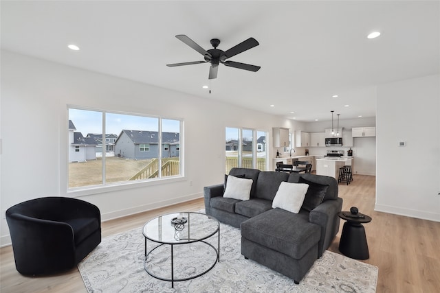 living room featuring ceiling fan, sink, and light hardwood / wood-style floors