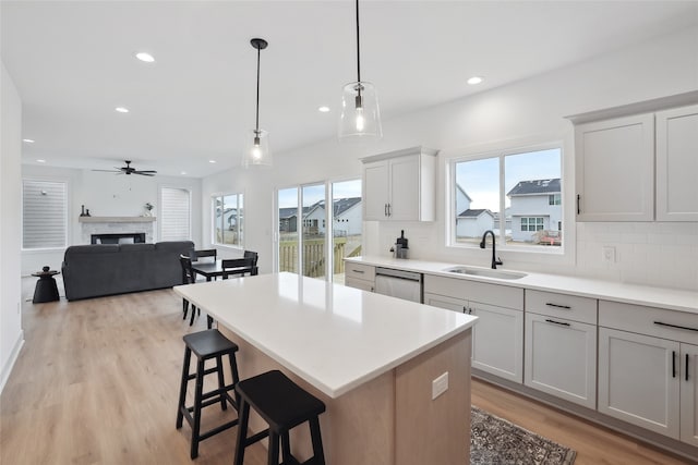 kitchen with dishwasher, sink, backsplash, hanging light fixtures, and a center island