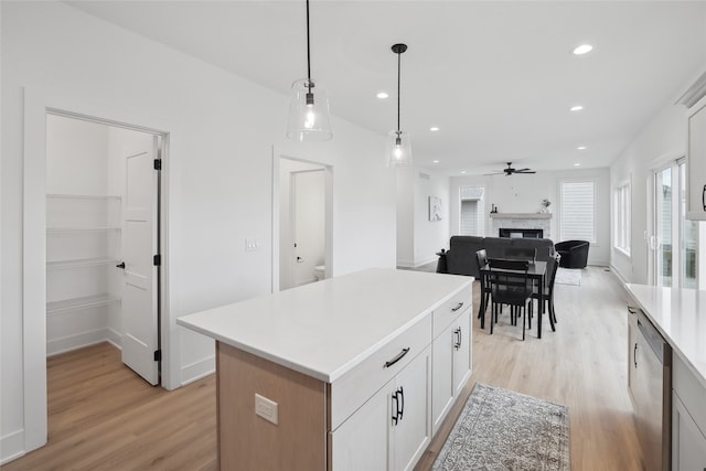 kitchen with white cabinetry, a center island, light hardwood / wood-style flooring, stainless steel dishwasher, and pendant lighting