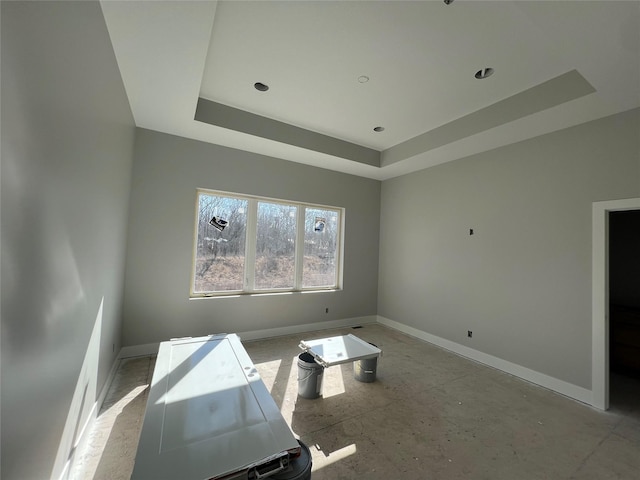 empty room featuring baseboards and a raised ceiling