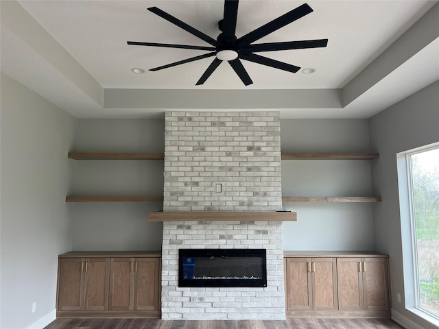 203 Hudson Ave, Van Meter, IA 50261 - unfurnished living room featuring wood finished floors, ceiling fan, a fireplace, and plenty of natural light