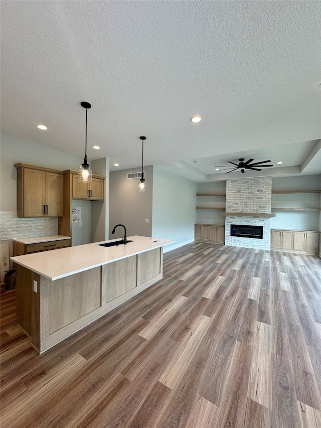 203 Hudson Ave, Van Meter, IA 50261 - kitchen featuring a sink, light wood-type flooring, a textured ceiling, a spacious island, and ceiling fan