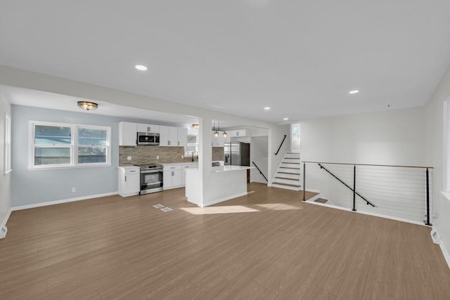 unfurnished living room featuring sink and light hardwood / wood-style flooring