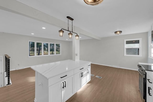 kitchen with pendant lighting, stainless steel range with electric stovetop, white cabinets, a kitchen island, and dark hardwood / wood-style flooring