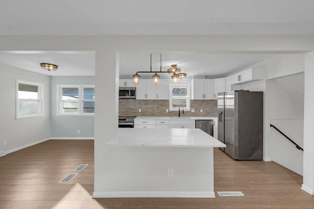 kitchen with backsplash, white cabinets, sink, light hardwood / wood-style flooring, and stainless steel appliances