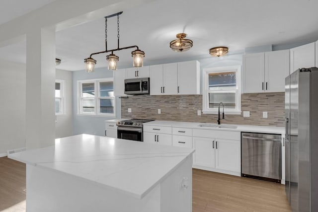 kitchen with a wealth of natural light, a center island, white cabinets, and stainless steel appliances