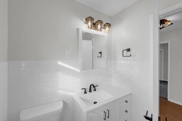 bathroom featuring hardwood / wood-style floors, vanity, tile walls, and toilet