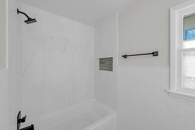 bathroom with tiled shower / bath combo and tile walls