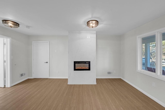 unfurnished living room with a fireplace and light wood-type flooring