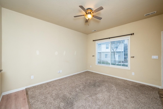 spare room featuring ceiling fan, light colored carpet, and a textured ceiling