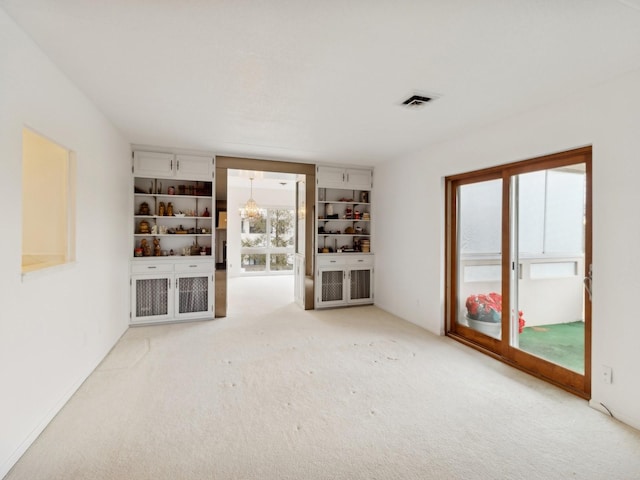 unfurnished living room with plenty of natural light, carpet floors, and a notable chandelier