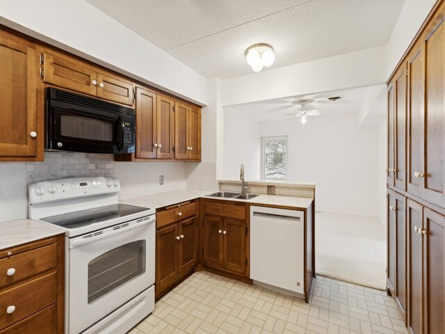 kitchen featuring kitchen peninsula, backsplash, white appliances, ceiling fan, and sink