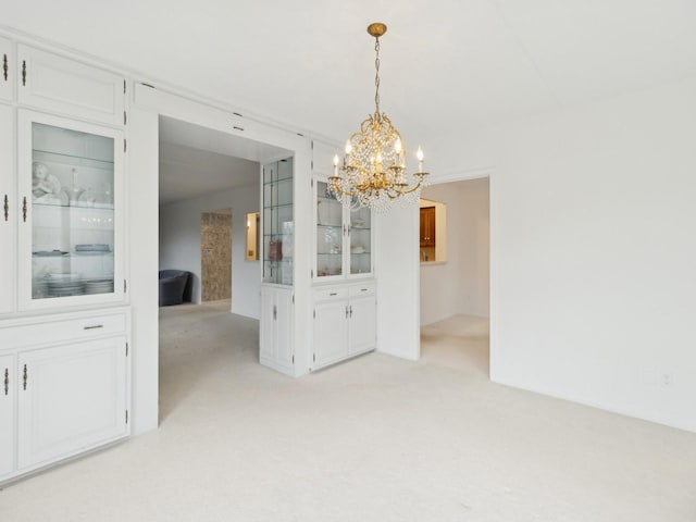 unfurnished dining area with a notable chandelier and light carpet