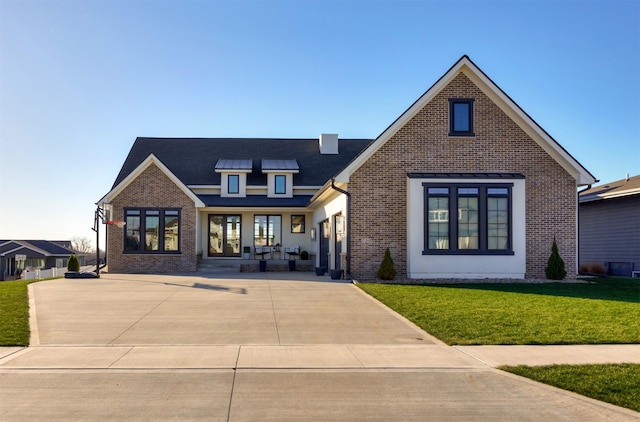 tudor-style house featuring covered porch and a front yard