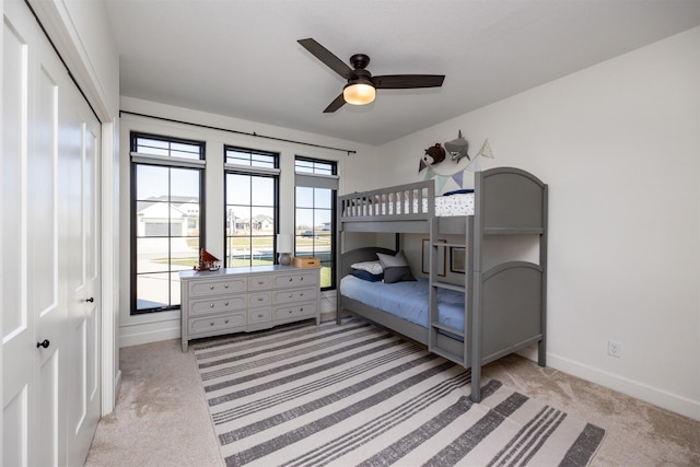 carpeted bedroom with ceiling fan and a closet