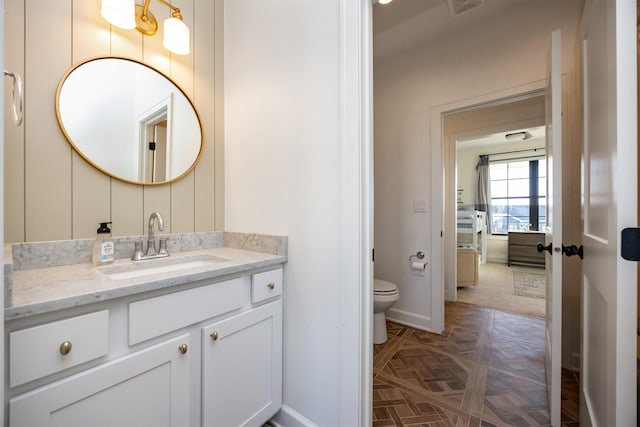 bathroom with vanity, parquet floors, and toilet