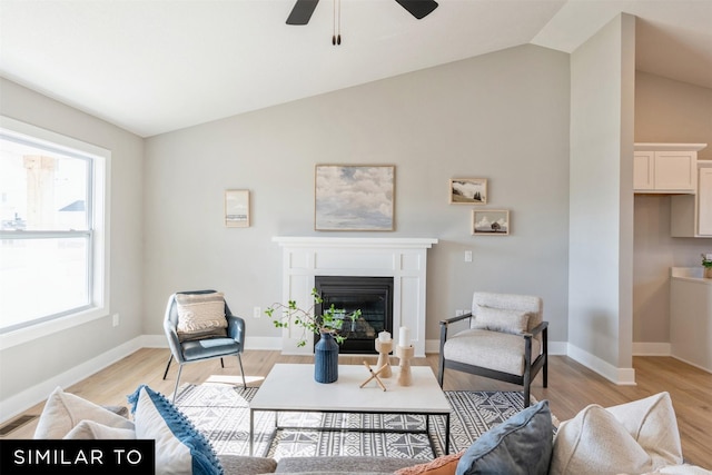 living room featuring light hardwood / wood-style flooring, vaulted ceiling, a wealth of natural light, and ceiling fan