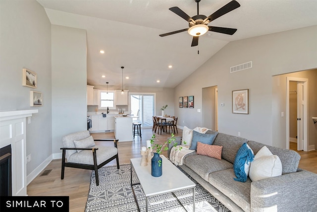 living room with ceiling fan, high vaulted ceiling, and light hardwood / wood-style floors