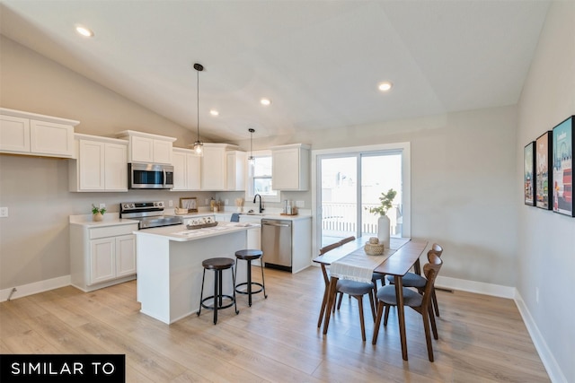 kitchen with a center island, hanging light fixtures, stainless steel appliances, lofted ceiling, and white cabinets