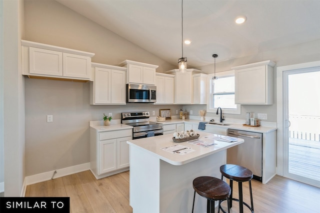 kitchen with hanging light fixtures, white cabinetry, sink, and appliances with stainless steel finishes