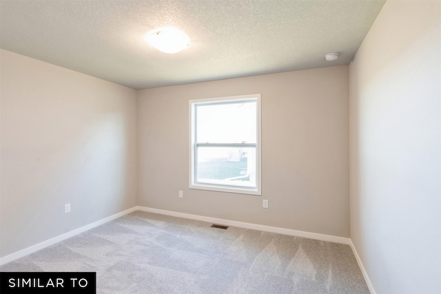 empty room with a textured ceiling and light colored carpet