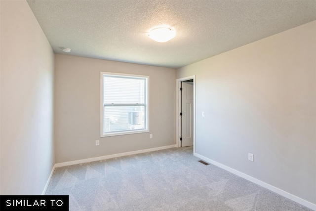 spare room with light carpet and a textured ceiling