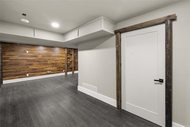 spare room with dark wood-type flooring and wooden walls