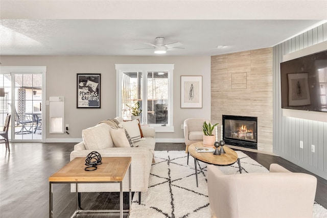 living room featuring hardwood / wood-style flooring, a tile fireplace, and ceiling fan