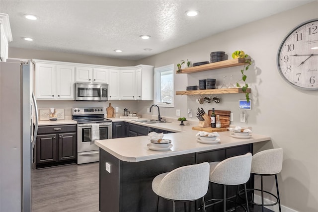 kitchen featuring a kitchen breakfast bar, stainless steel appliances, kitchen peninsula, and white cabinets