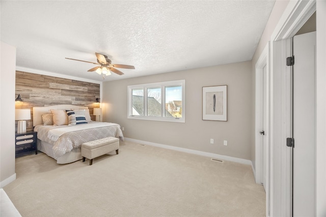 bedroom with light carpet, ceiling fan, wooden walls, and a textured ceiling