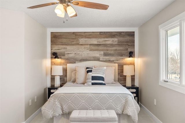 bedroom featuring ceiling fan, wooden walls, and a textured ceiling