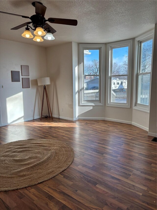 unfurnished living room with dark hardwood / wood-style flooring, a textured ceiling, and ceiling fan