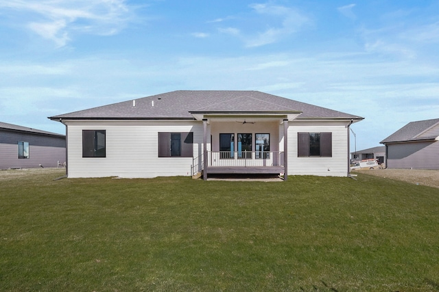 back of house with a ceiling fan, a lawn, and a shingled roof