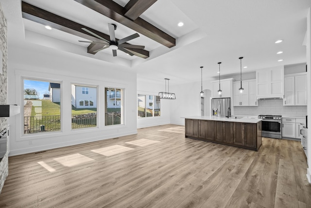 kitchen with appliances with stainless steel finishes, light countertops, open floor plan, recessed lighting, and backsplash