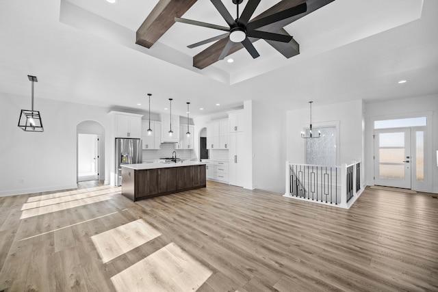 kitchen with open floor plan, arched walkways, light countertops, a ceiling fan, and tasteful backsplash