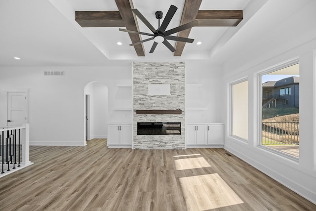 unfurnished living room featuring ceiling fan, arched walkways, healthy amount of natural light, light wood-style flooring, and recessed lighting