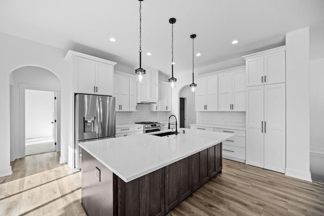 kitchen with white cabinets, an island with sink, appliances with stainless steel finishes, and light wood-type flooring