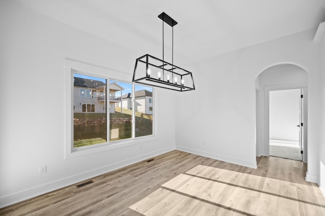 unfurnished dining area with light hardwood / wood-style flooring and a notable chandelier