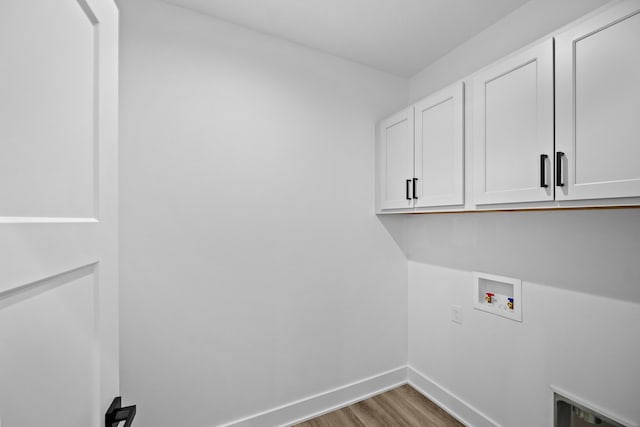washroom with cabinet space, washer hookup, baseboards, and wood finished floors