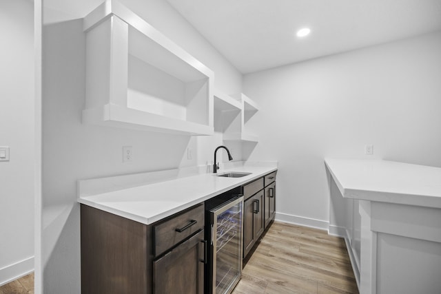 kitchen featuring dark brown cabinets, light wood-type flooring, wine cooler, and sink