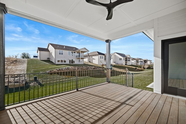 wooden terrace with a residential view, ceiling fan, and a lawn