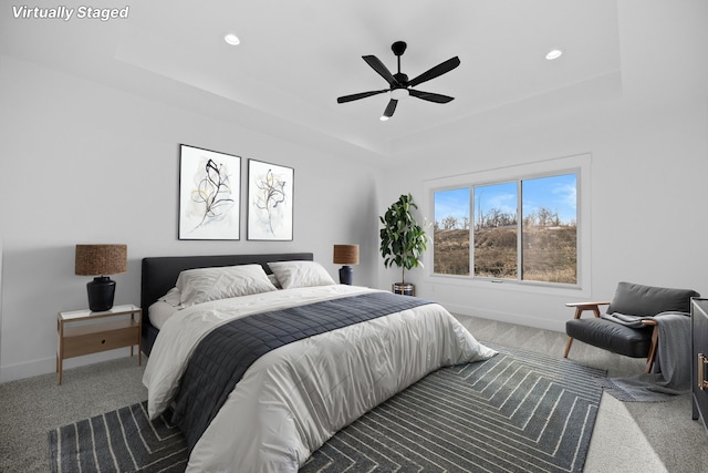 carpeted bedroom featuring a raised ceiling, baseboards, recessed lighting, and ceiling fan