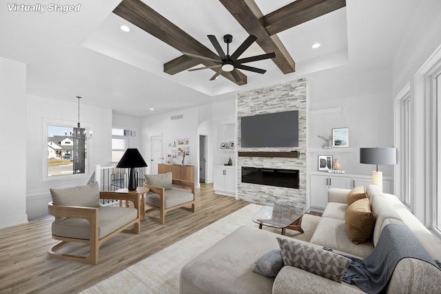 living area featuring a ceiling fan, coffered ceiling, light wood-type flooring, recessed lighting, and a stone fireplace