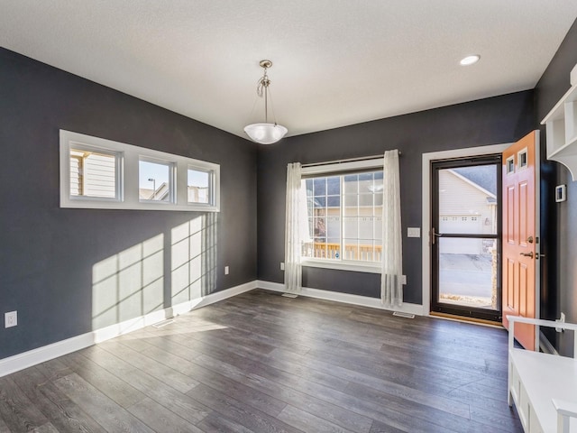 unfurnished dining area with a textured ceiling and dark wood-type flooring