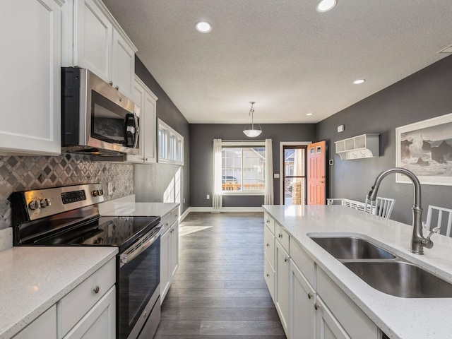 kitchen featuring sink, light stone countertops, stainless steel appliances, and hanging light fixtures