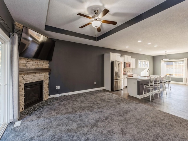 unfurnished living room featuring a textured ceiling, ceiling fan, a fireplace, and dark hardwood / wood-style floors