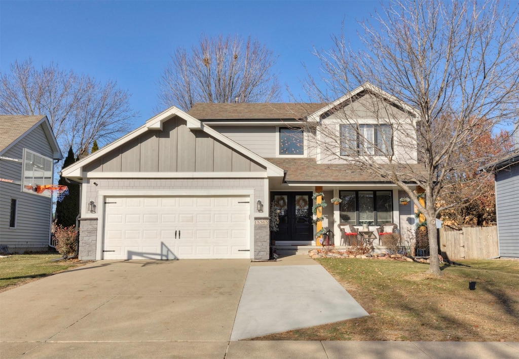 view of front of home featuring covered porch, a garage, and a front yard