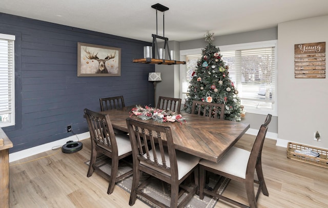 dining room featuring light hardwood / wood-style floors and wooden walls